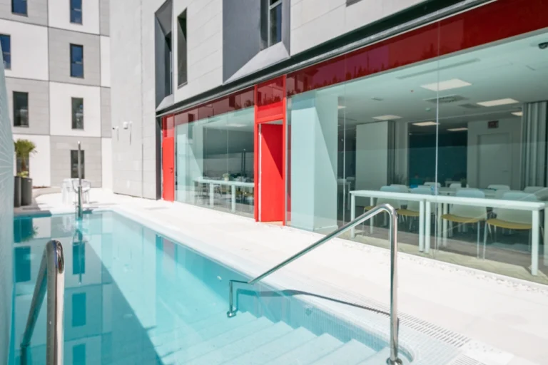 Piscina exterior en residencia moderna con zonas comunes y diseño contemporáneo.